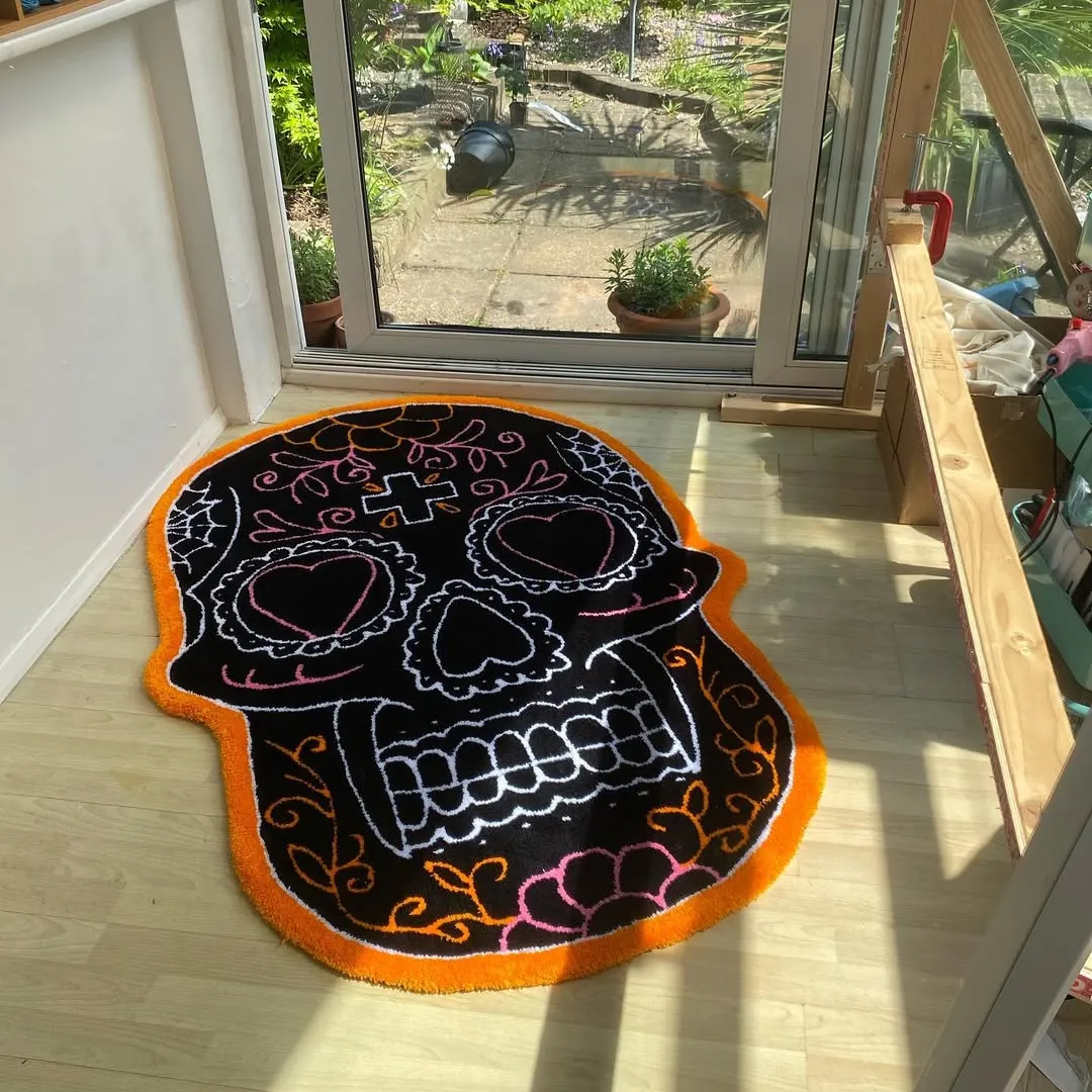 Day of the Dead sugar skull rug with black base and colorful orange, pink, and white floral details on a light wood floor.