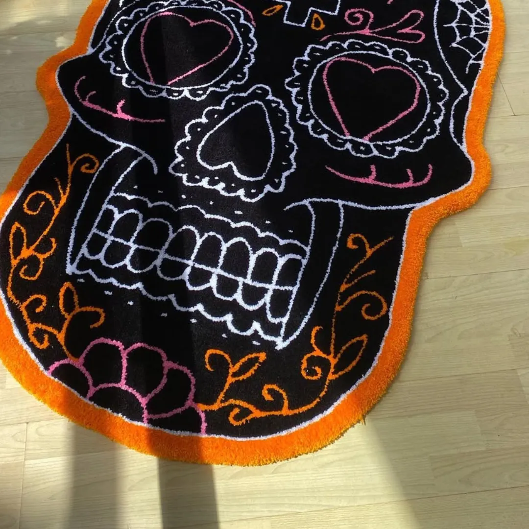 Hand tufted sugar skull rug with black base and colorful orange, pink, and white floral details on a light wood floor.