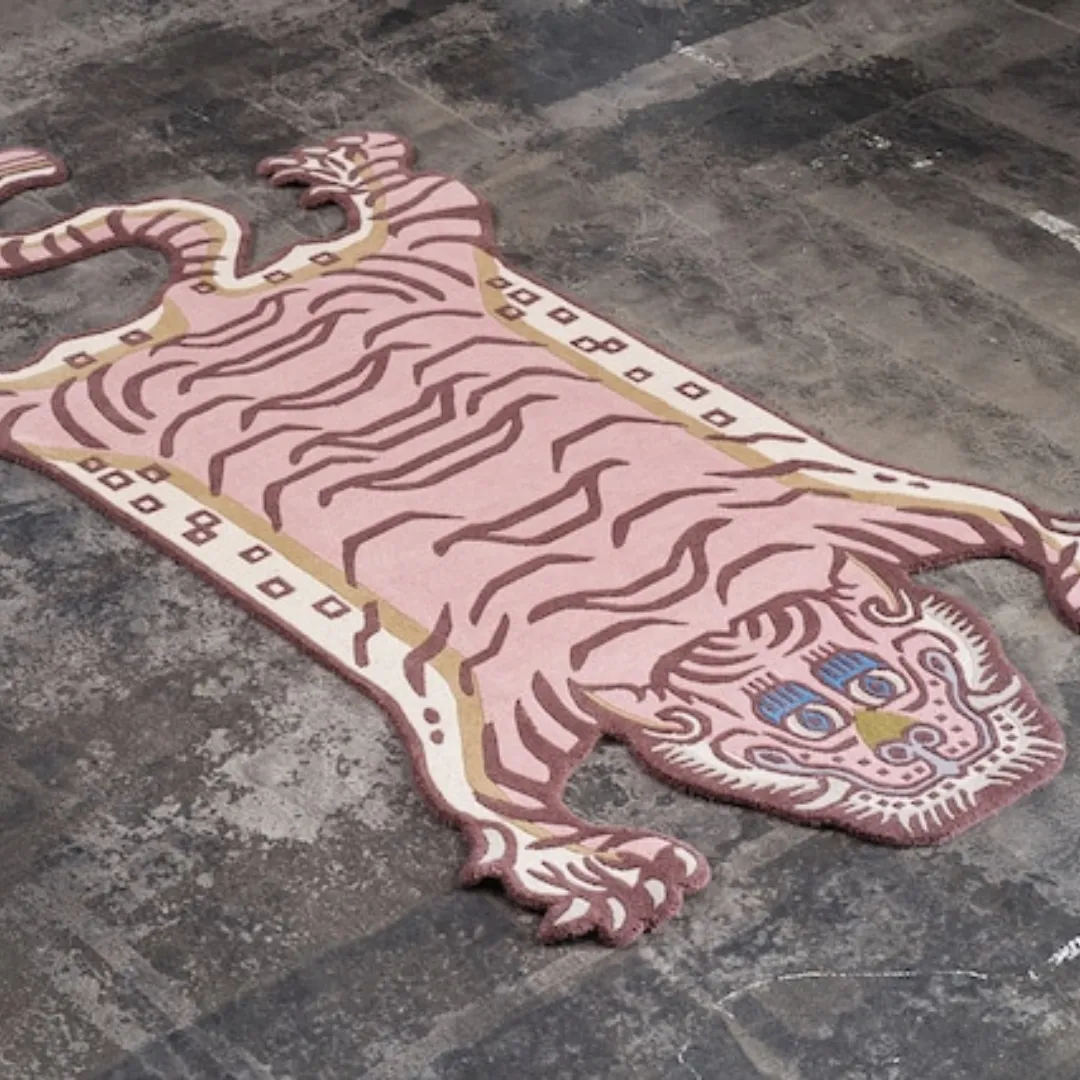 Pink Tibetan tiger rug with bold stripes, blue eyes, and a stylized tiger face, hand tufted in wool.