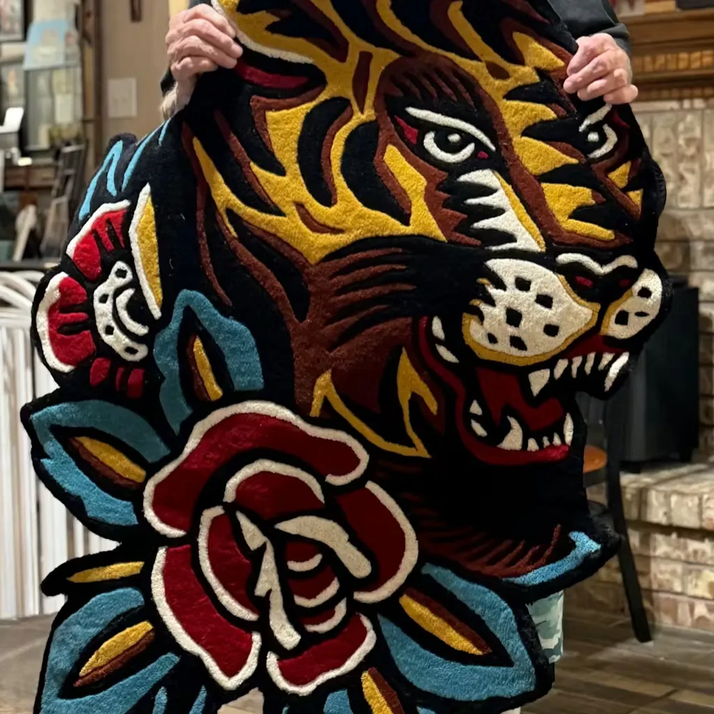 Rosette Blocks Floral Checkerboard Rug Flat Lay A person holding up the large Bert Grimm Tiger rug, showcasing the vibrant gold and red colors and detailed hand tufted craftsmanship of the old school flash art design.