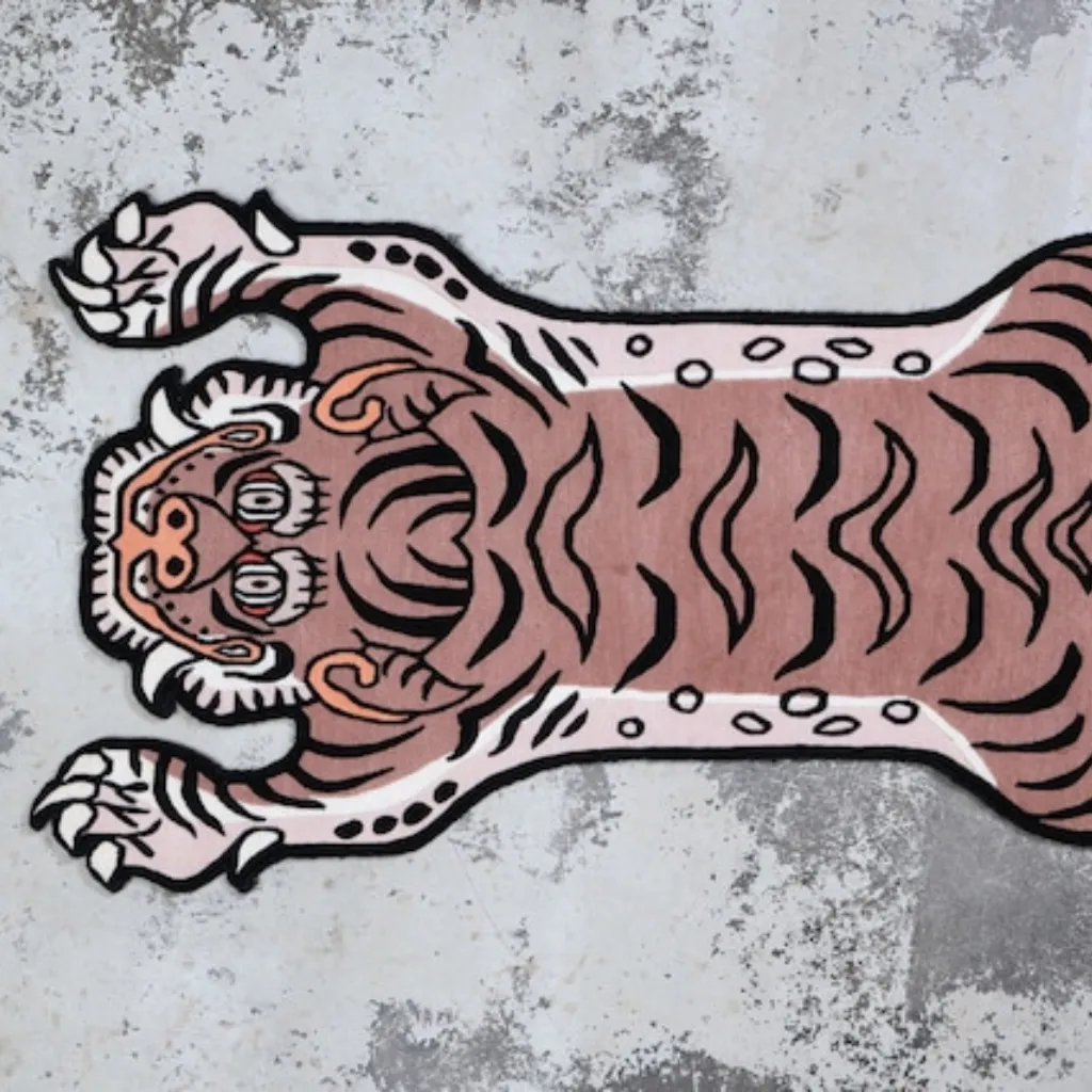blush prowl pink tiger skin shaped rug wood floor High angle view of the full Blush Prowl rug placed on a rustic wooden floor, showcasing the traditional Tibetan tiger skin shape reimagined in a contemporary pastel pink and black colorway.