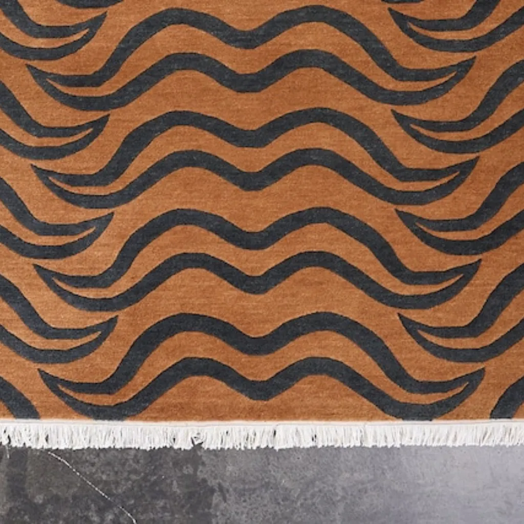 feral fur brown tibetan tiger rug head detail Close-up top down view of the Feral Fur Tibetan Rug, focusing on the stylized tiger face with intense eyes and bold black wavy stripes set against a rich natural brown and tan background.