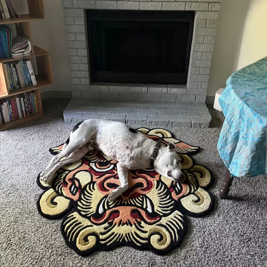 hand tufted lion dog rug with pet A large white dog sleeping comfortably on the Orange Foo Dog rug, demonstrating the soft wool texture and the generous size of the custom shape.