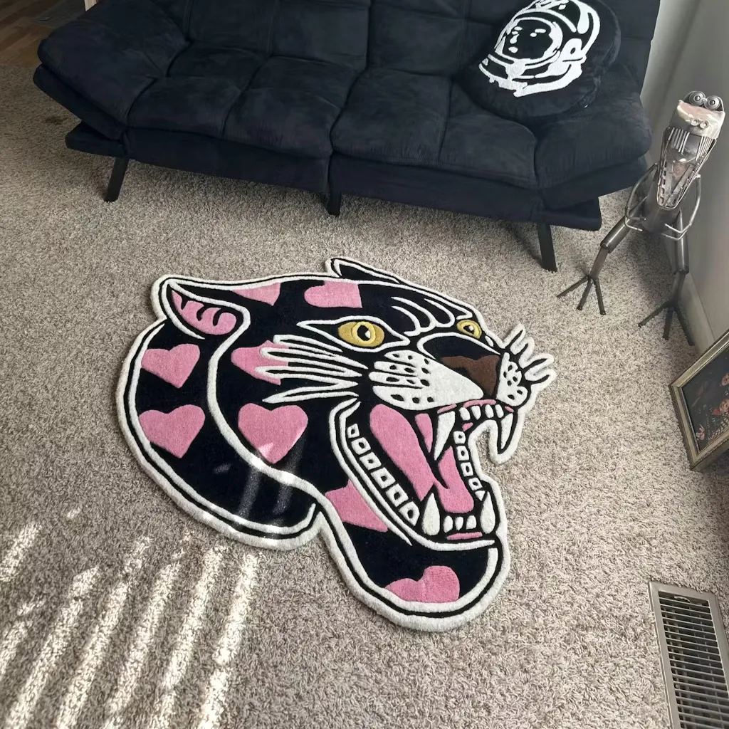 Pink Panther Shaped Rug Living Room Decor High angle view of the Pink Panther Head rug placed on a carpeted floor near a black futon, adding a bold tattoo-inspired accent to the room.