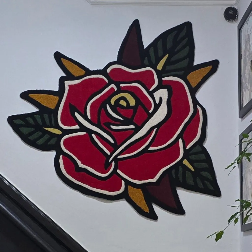 Red Rose Traditional Rug Wall Hanging The Red Rose Traditional rug mounted on a white wall as tapestry art, showcasing the bold black outlines and vibrant crimson petals of the old school tattoo design.