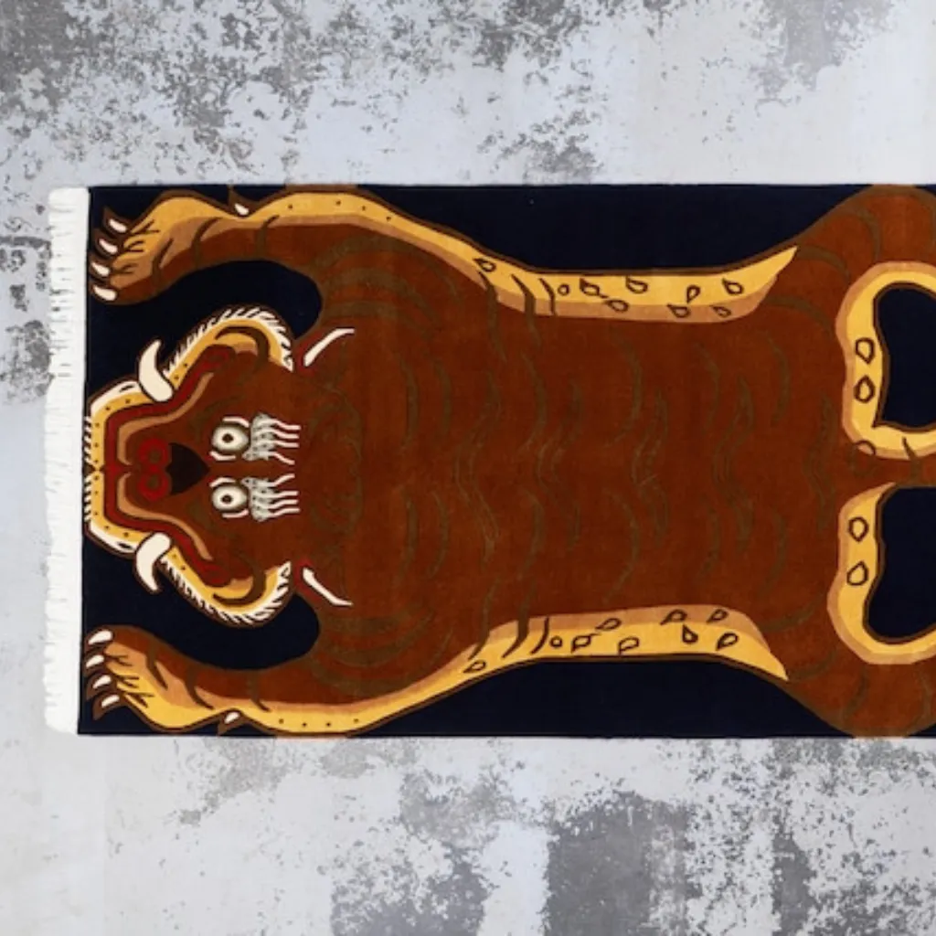 rooted fang moss green tiger skin shaped rug wood floor High angle view of the full Rooted Fang rug placed on a rustic wooden floor, showcasing the traditional Tibetan tiger skin shape reimagined in an earthy green and black colorway.