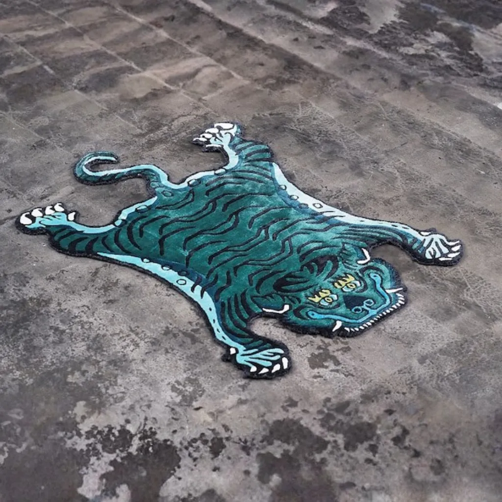 tidal prowl hand tufted wool teal tiger rug design Angled view of the Tidal Prowl rug, highlighting the dense hand-tufted wool texture and the wandering black stripe pattern on a cool teal field.