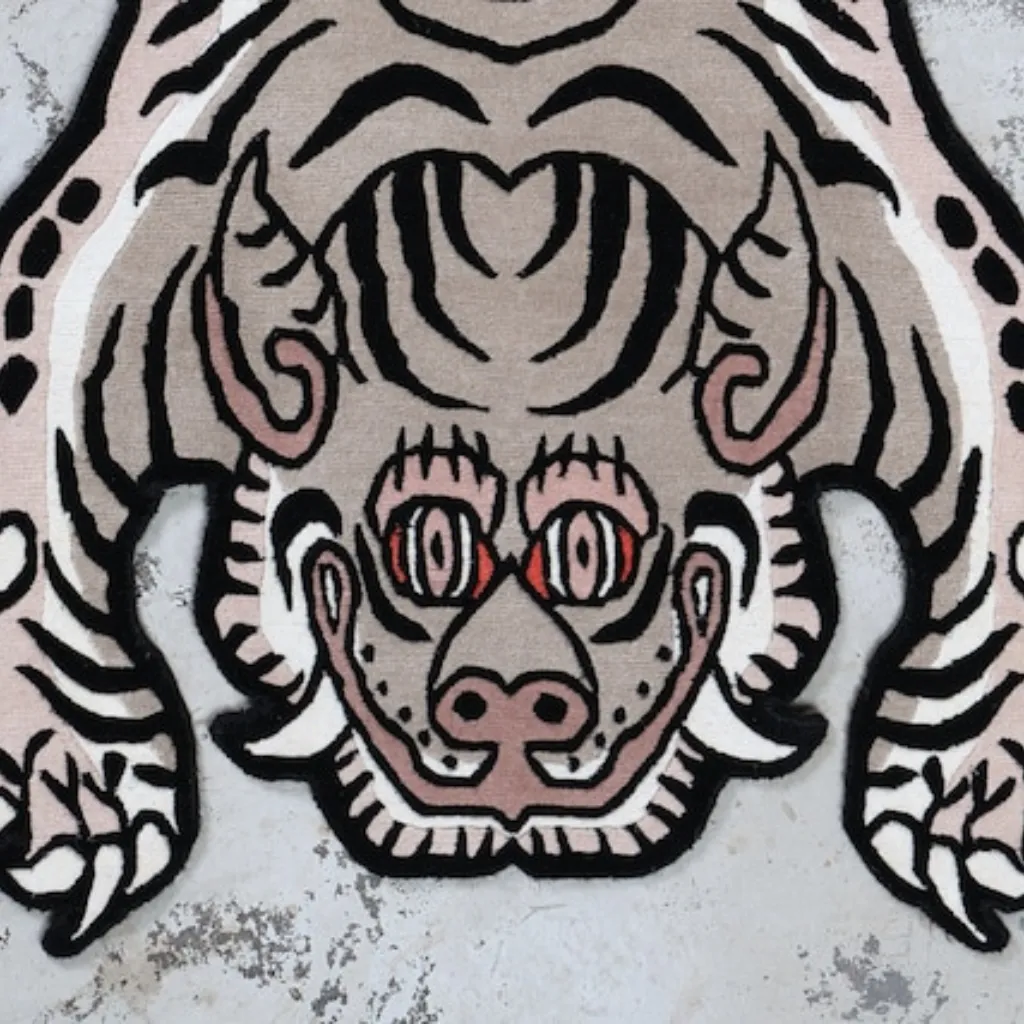 whispered paws white tibetan tiger rug head detail High angle view of the full Whispered Paws rug placed on a rustic wooden floor, showcasing the traditional Tibetan tiger skin shape reimagined in a striking monochrome white and black colorway.