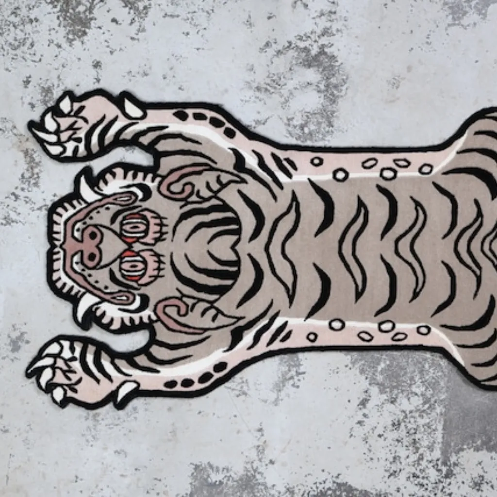 whispered paws white tiger skin shaped rug wood floor Close-up top down view of the Whispered Paws Tibetan Rug, focusing on the stylized white tiger face with soft grey accents, piercing eyes, and bold black wavy stripes.