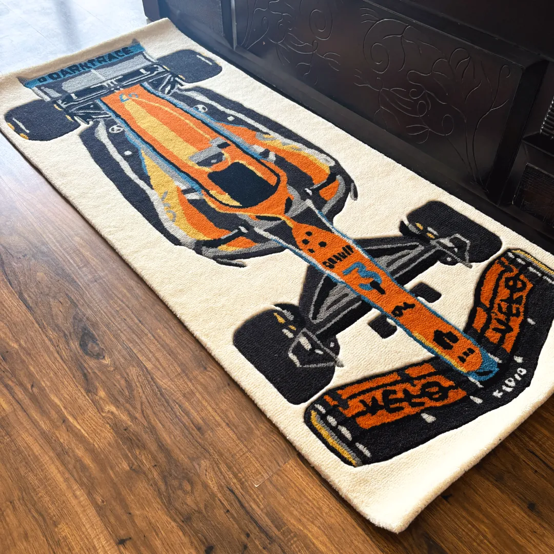 ignite rush orange race car runner rug Perspective view of the Ignite Rush runner rug placed on a wooden floor, featuring a detailed tufted illustration of an orange and blue Formula 1 race car on a cream background.
