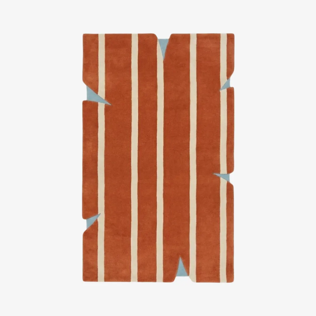 bond break rug top Top-down view of the Bond Break rug featuring a bold terracotta orange field with vertical cream stripes and deep triangular notches cut into the irregular silhouette, revealing light blue accents.