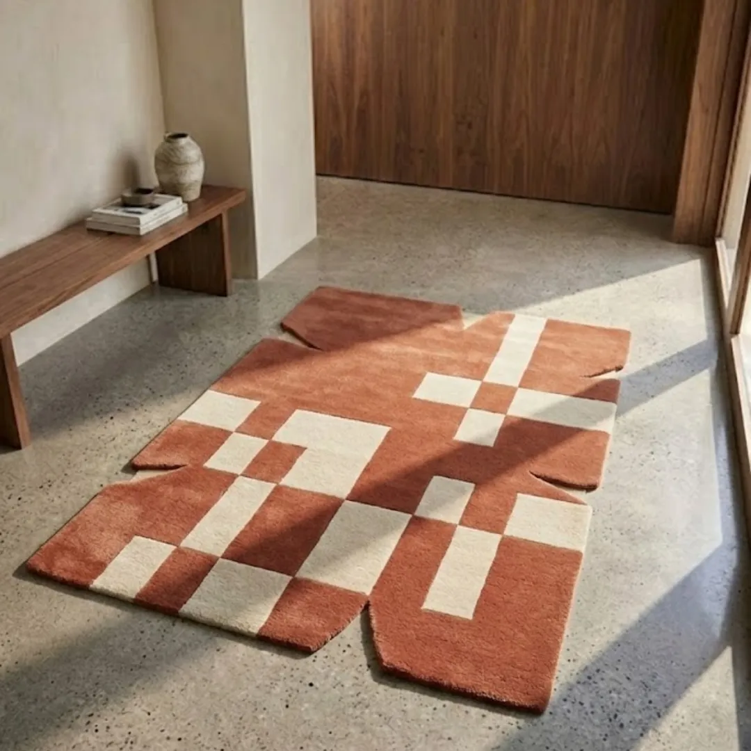 desert codec rug lifestyle Perspective lifestyle view of the Desert Codec rug placed on a polished concrete floor, showcasing the bold terracotta and cream digital-inspired pattern and its architectural jagged border.