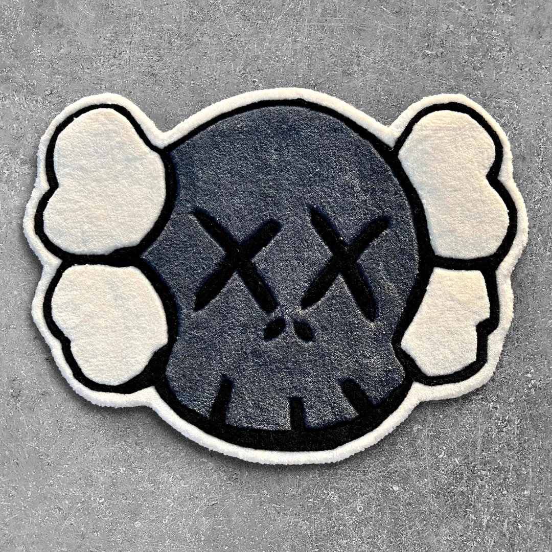 gravine emblem rug top Top-down view of the shaped Gravine Emblem rug on a textured concrete surface, featuring a streetwear-inspired grey skull design with signature black XX eyes and white crossbone details.