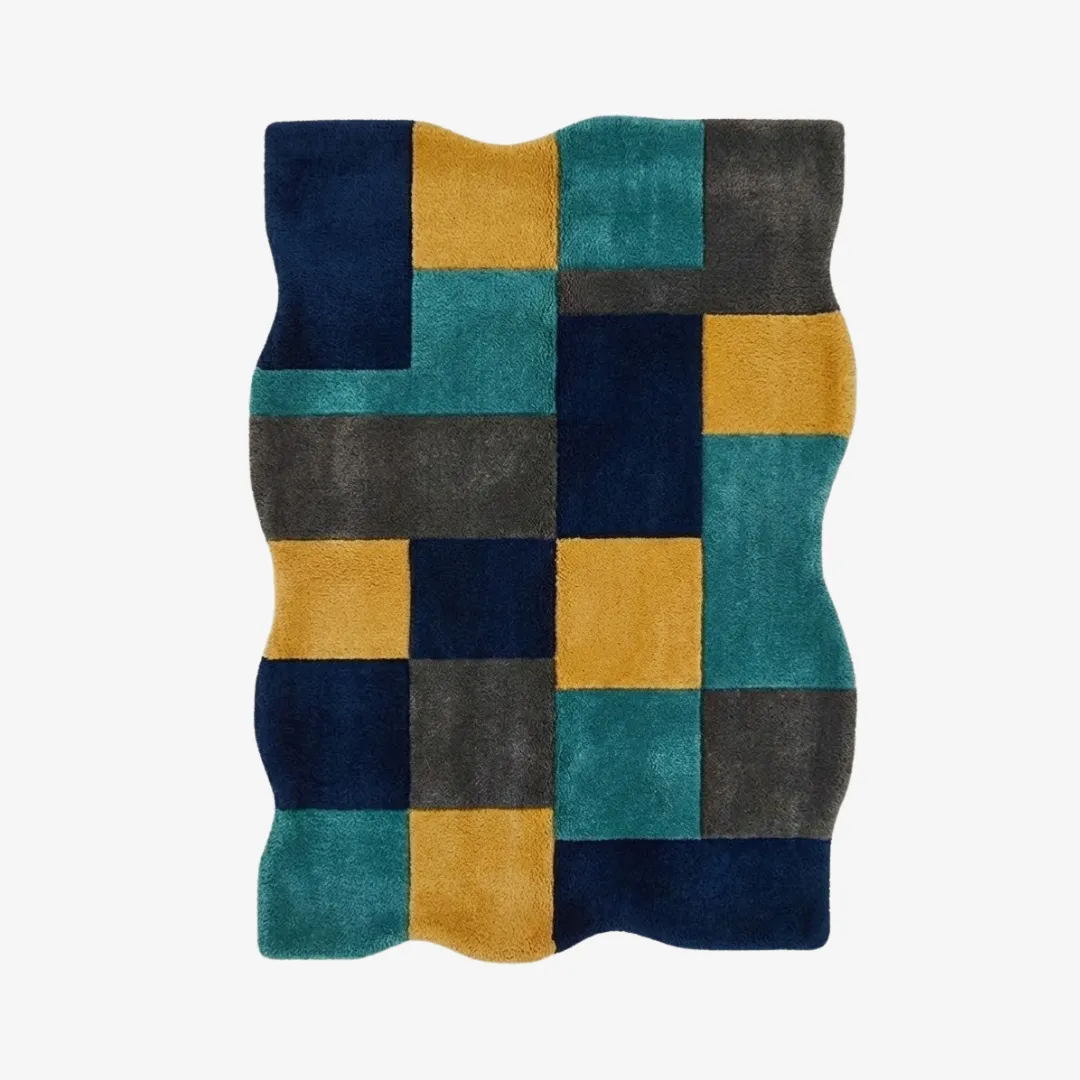 harbor mosaic rug top Top-down view of the Harbor Mosaic rug featuring an irregular wavy silhouette and a geometric patchwork design of dark blue, teal, mustard yellow, and charcoal grey rectangular blocks.
