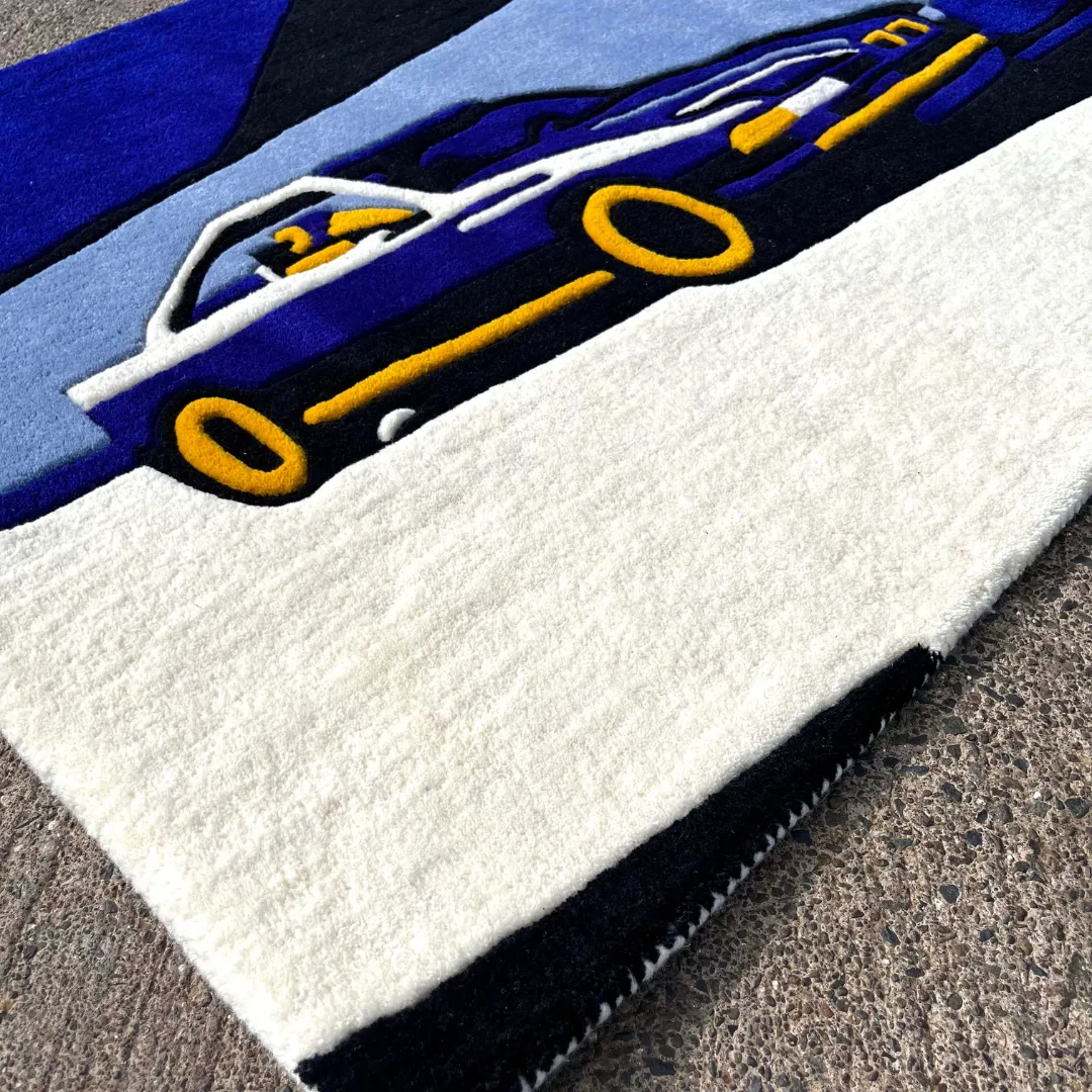 noctra veil rug detail Close-up texture detail of the Noctra Veil rug, highlighting the dense, plush hand-tufted wool pile of the blue sports car design and the sharply carved yellow accents.