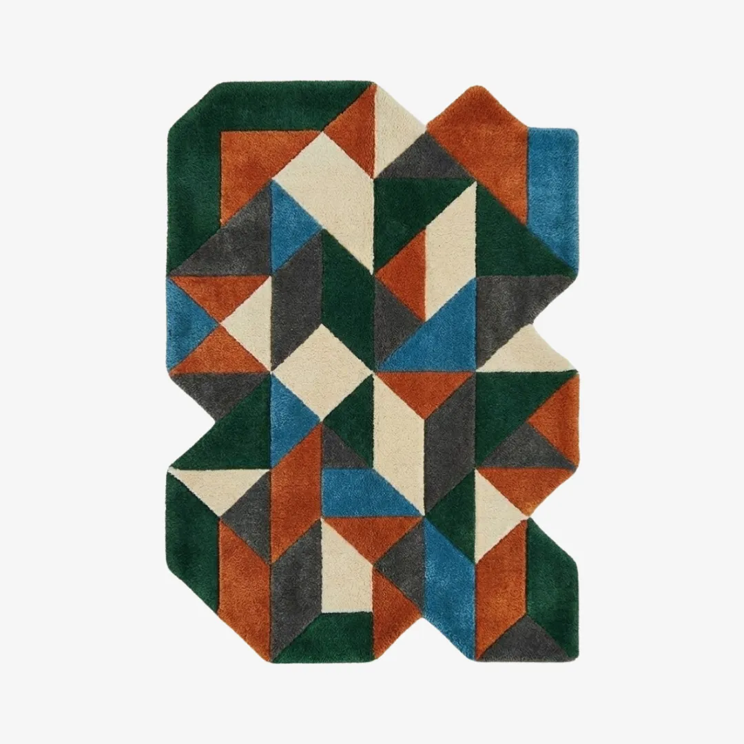 prism nomad rug top Top-down view of the Prism Nomad rug showcasing its complex, jagged irregular silhouette and a vibrant geometric pattern of intersecting triangles in emerald green, burnt orange, ivory, and slate grey.