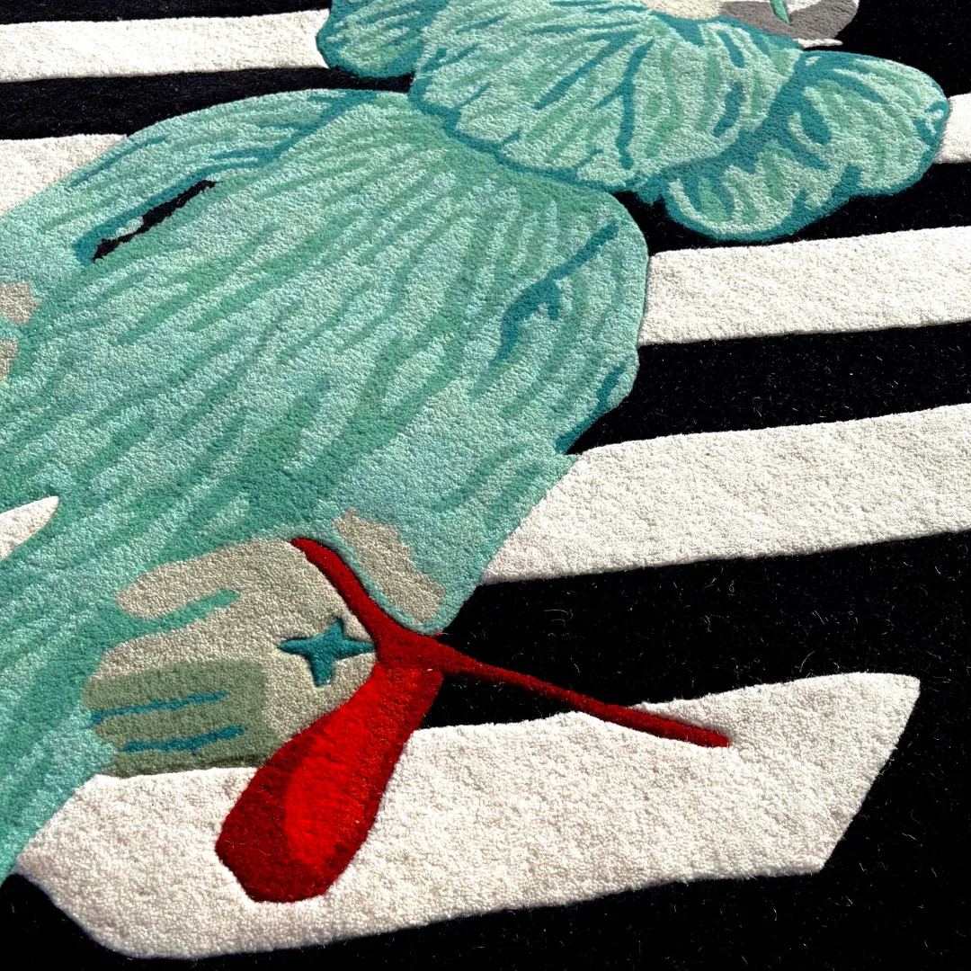 virx column rug hand detail Close-up texture detail of the Virx Column rug, emphasizing the deeply carved, tufted wool pile of the character's mint green hand holding a bright red balloon over the graphic black and white striped base.