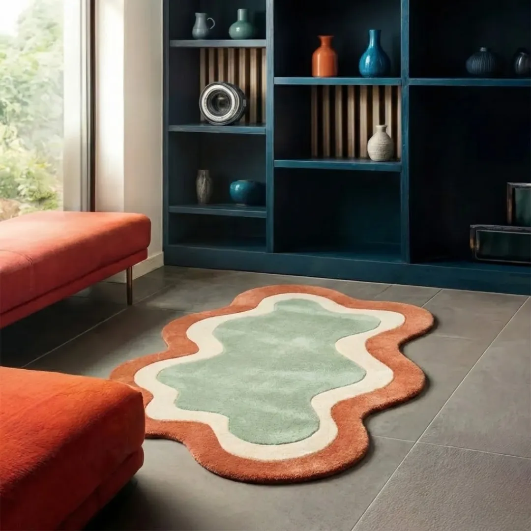 wellonest rug lifestyle Perspective lifestyle view of the Wellonest rug on a grey tile floor, styled with orange velvet benches to highlight its unique wavy border and warm earth-toned palette.