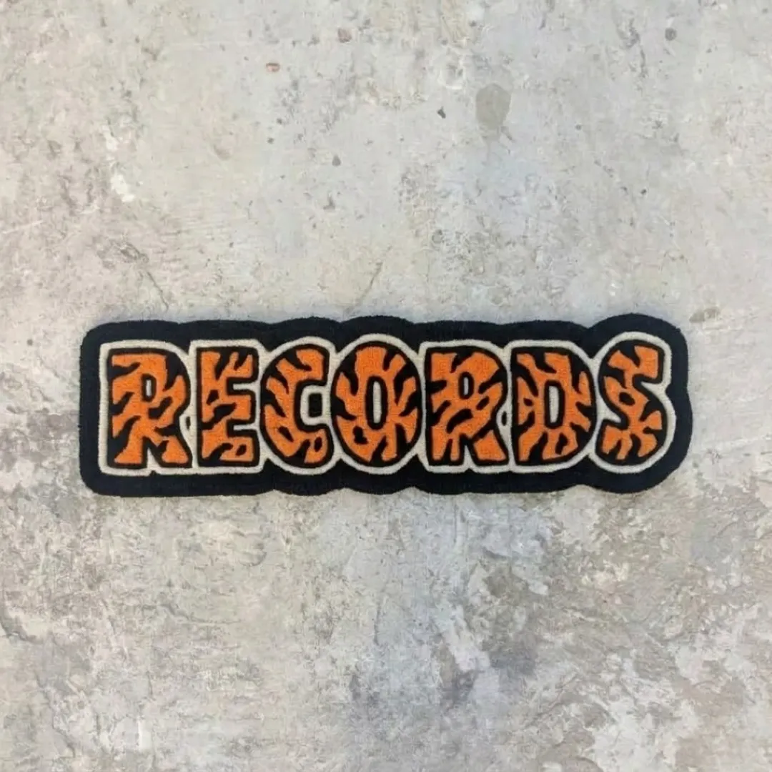 orange record rug product shot Full top-down shot of the hand-tufted Orange Record Rug with custom typography on a concrete floor.