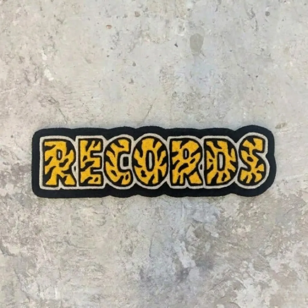 record rug product shot Full top-down view of the yellow and black hand-tufted Record Rug with custom typography on a concrete floor.